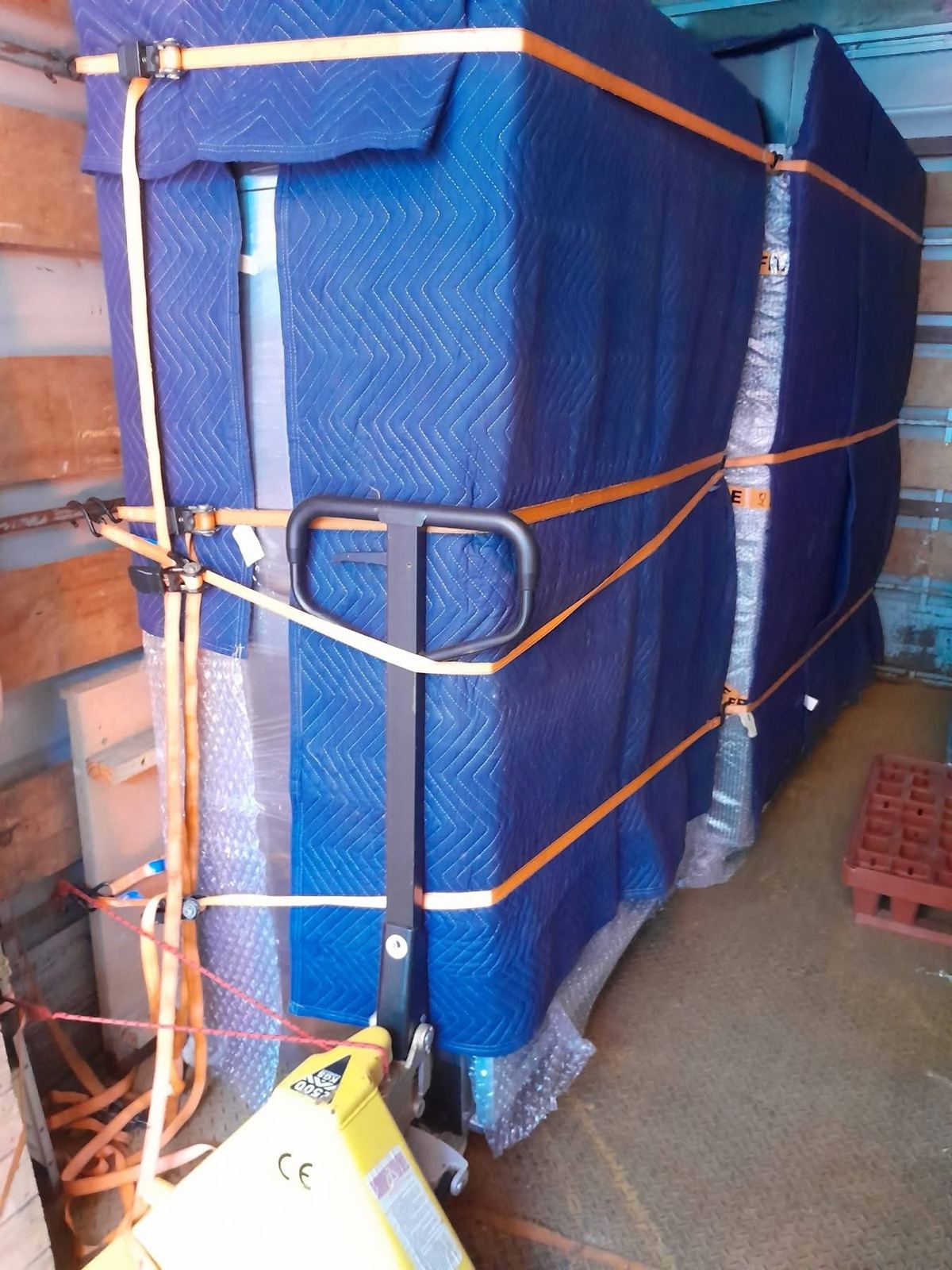 Furniture wrapped in blue moving blankets and strapped for transport